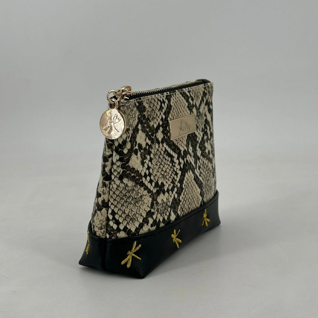 Snakeskin patterned pouch with gold accents on a gray background